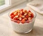 Budino di chia e yogurt in un bicchiere con fragole a pezzetti e mandorle a lamelle tostate